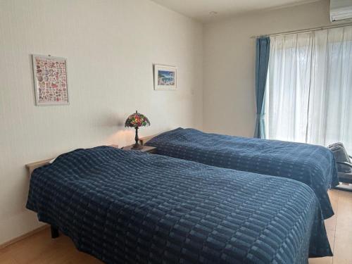 two beds in a bedroom with blue comforter at Riverside Garden -kumanokodo-chikatsuyu- in Tanabe