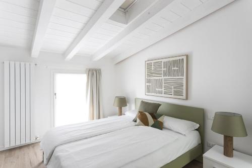 a white bedroom with a large bed and a window at Maison Bellini 4 in Toscolano Maderno