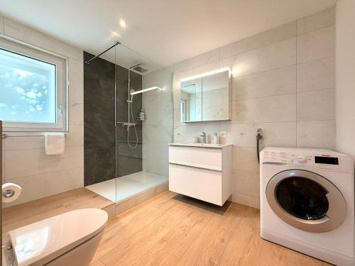 a bathroom with a washing machine and a shower at Modernes Apartment - Lakeview Sunnmatte in Leissigen