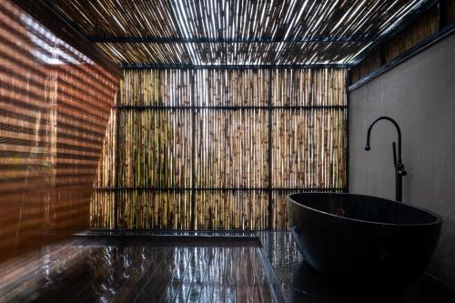 a bathroom with a tub and a bamboo wall at Amaaranth Goa in Varca