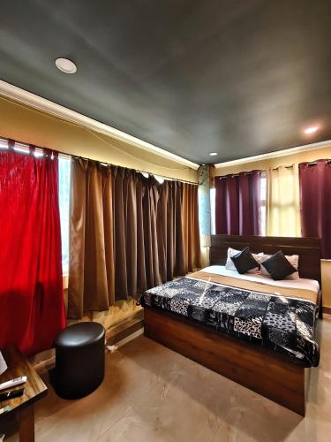 a bedroom with a bed with red curtains at Hotel Heavens in Dum-Dum Junction