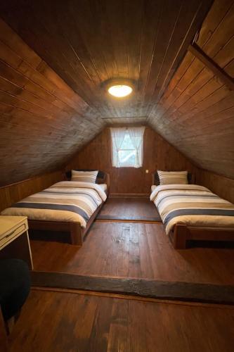 two beds in a wooden room with a window at Chalupa Lipka in Kolárovice