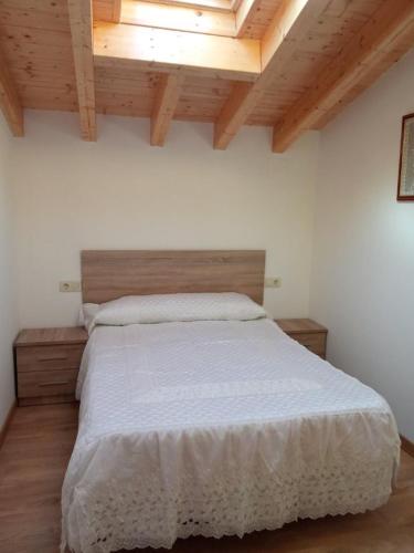 a bedroom with a large white bed with wooden ceilings at Casa Abuela Antolina in La Horcajada