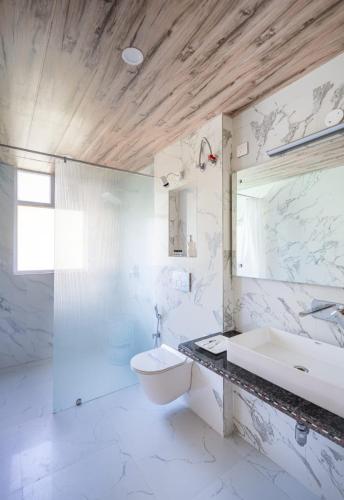 a white bathroom with a sink and a toilet at Manali Golden Valley in Manāli