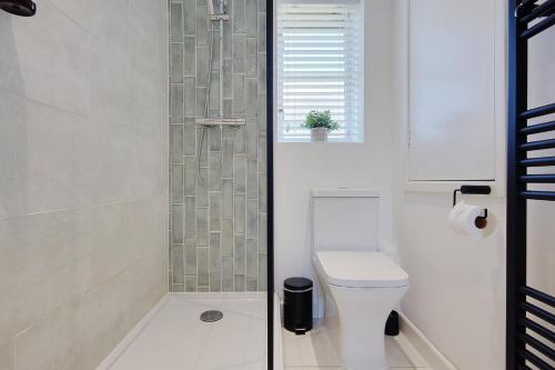 a bathroom with a toilet and a glass shower at The Nook - Cosy coastal retreat near Sandbanks in Poole