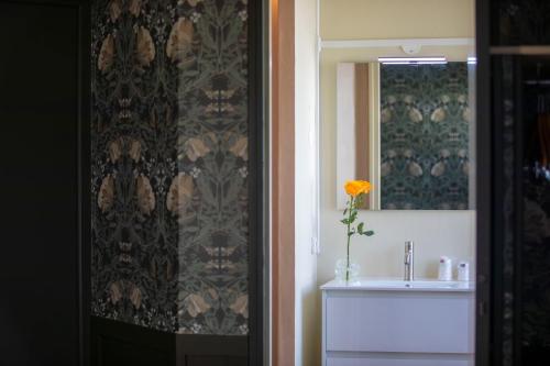 a bathroom with a sink and a vase with a yellow flower at Relais Touraine Sologne in Noyers-sur-Cher
