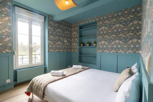 a blue bedroom with a bed and a window at Relais Touraine Sologne in Noyers-sur-Cher