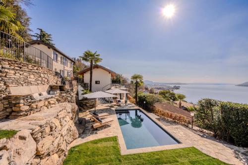 a swimming pool in the yard of a house with a stone wall at Villa Suna Paradiso in Verbania