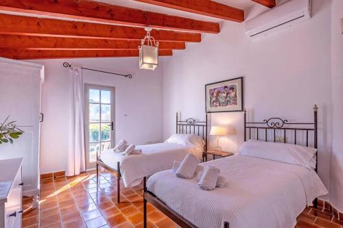 two beds in a room with white walls and wooden ceilings at Villa Rafaleta by Villa Plus in Pollença