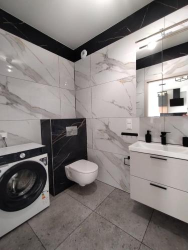 a bathroom with a washing machine and a toilet at Nowoczesny Apartament 400 M Od Plaży Prywatny Ogródek Ełk in Ełk
