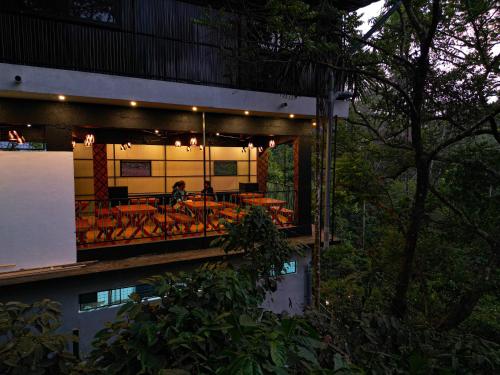 a building with a balcony with tables and chairs at Kashmeeram Vythiri Wayanad Premium Pool Resort in Vayittiri