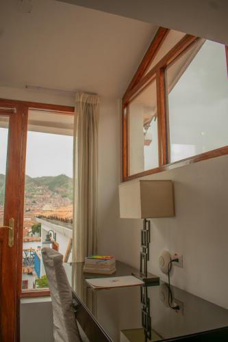 a room with a desk with a lamp and a window at Tocuyeros Boutique Hotel in Cusco