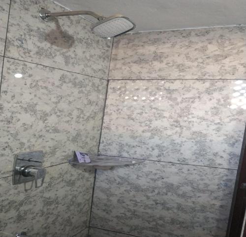 a shower with a shower head and a shelf in a bathroom at Landmark Residency in Atirāmpattinam
