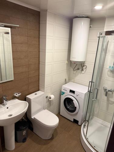 a bathroom with a toilet sink and a washing machine at ORBI 4 Seasons ApartHotel in Batumi
