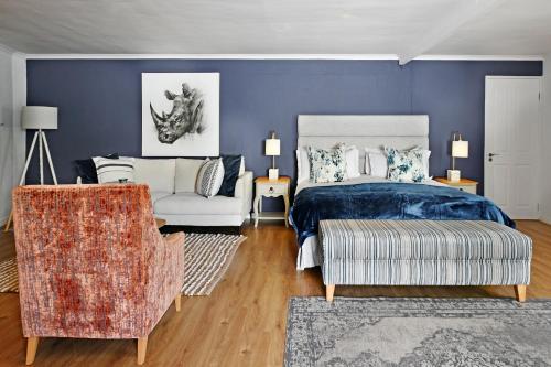 a blue bedroom with a bed and a chair at Mirabelle Guesthouse in Franschhoek
