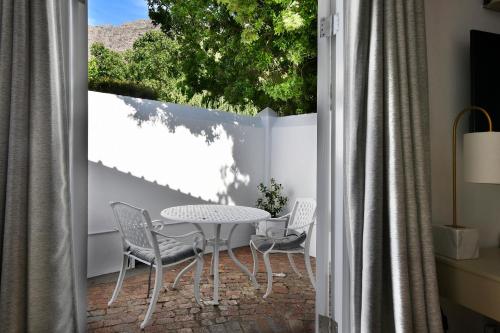 a patio with a table and chairs and a window at Mirabelle Guesthouse in Franschhoek