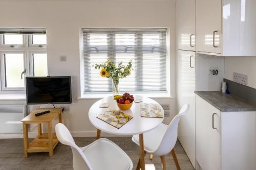a kitchen with a white table and white chairs at The Bake House in Worthing