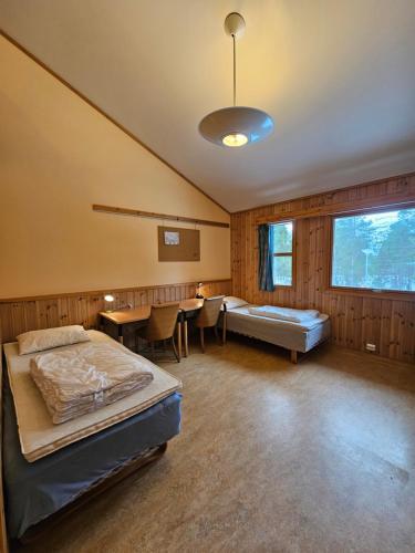 a bedroom with two beds and a table and chairs at Alta Folkehøgskole in Alta