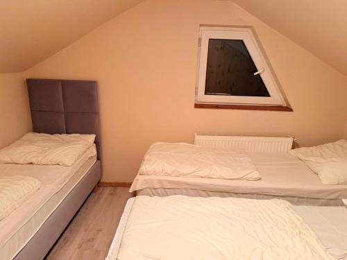 two twin beds in a room with a window at Na Pograniczu domek w górach in Lasowka