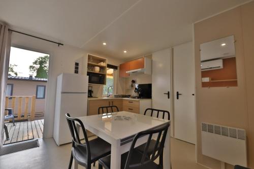 a kitchen and dining room with a white table and chairs at Vertacoflav - Bungalow - 6 couchages in Carry-le-Rouet
