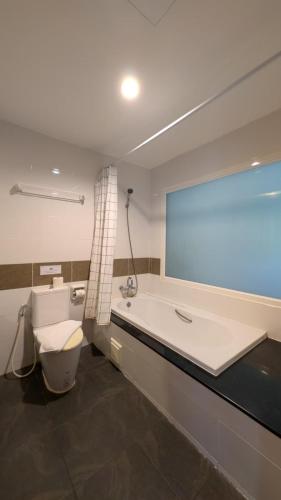 a bathroom with a tub and a toilet and a large window at Diamond Crown Patong in Patong Beach