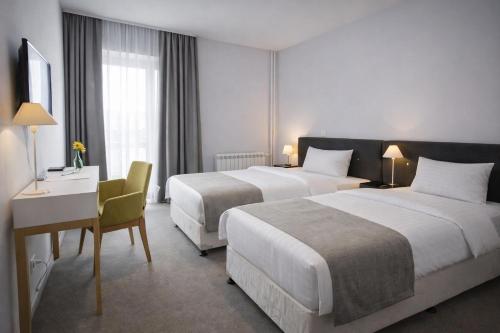 a hotel room with two beds and a desk at Nobel Inn Hotel in Belgrade