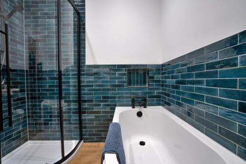 a bath tub in a bathroom with blue tiles at Finest Retreats - East Bank in Matlock