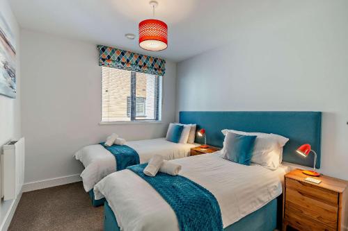 a bedroom with two beds and a window at 8 Putsborough - Luxury Apartment at Byron Woolacombe, only 4 minute walk to Woolacombe Beach! in Woolacombe