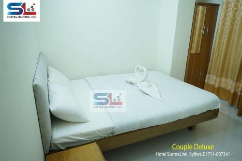 a bed with a white pillow with a bow on it at Hotel SurmaLink in Sylhet