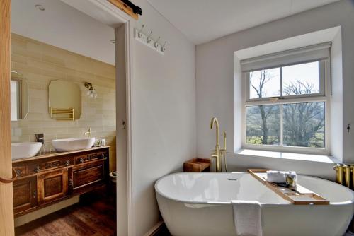 a bathroom with a tub and two sinks and a window at Finest Retreats - Blackton Farmhouse in Barnard Castle