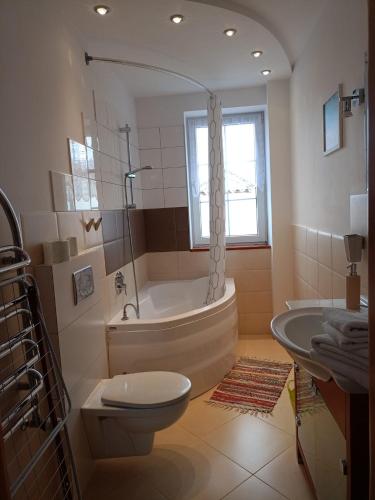 a bathroom with a tub and a toilet and a sink at Darłowska 49A in Dąbki