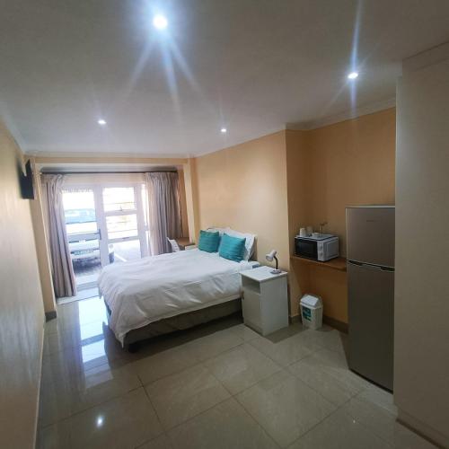 a hotel room with a bed and a refrigerator at 75 on Albert Guesthouse in Gqeberha