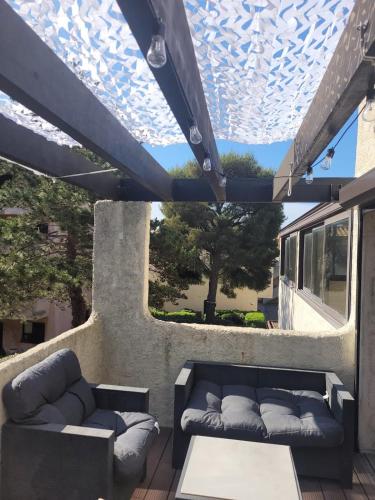 Un patio con sofás y una mesa y una ventana. en Le nid bleu, en Sausset-les-Pins