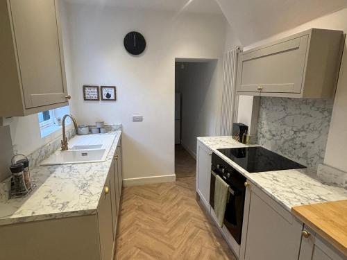 a kitchen with white cabinets and a sink at Crown Cottage in Belper