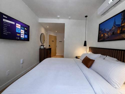 a bedroom with a large white bed with a tv on the wall at Room with a King-Size Bed Downtown Quebec in Quebec City