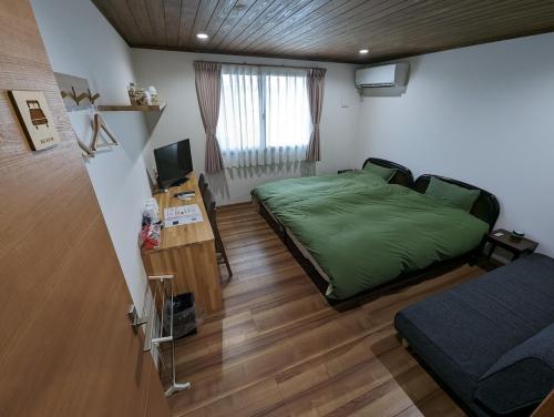 a bedroom with a green bed and a television at ゲストハウスきーず in Nishio