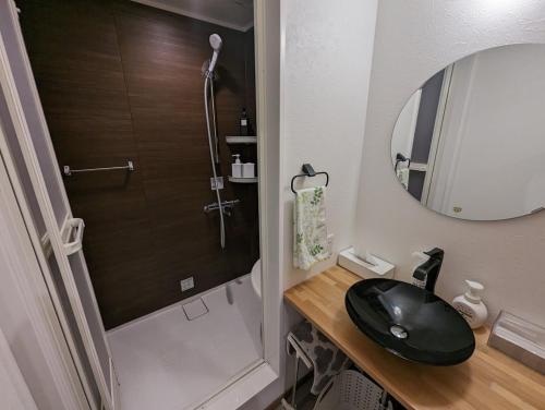 a bathroom with a black sink and a mirror at ゲストハウスきーず in Nishio