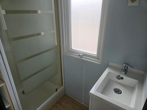 a white bathroom with a sink and a window at Camping Arenas in Bareyo