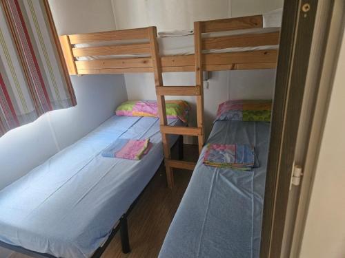 two bunk beds in a small room with a ladder at Camping Arenas in Bareyo