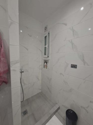 a bathroom with a shower with white marble walls at Varkiza Pines Apartment in Varkiza