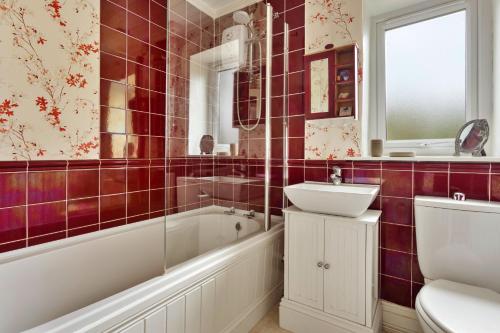 a bathroom with red tiled walls and a tub and sink at Finest Retreats - Vine Barn in Bellerby