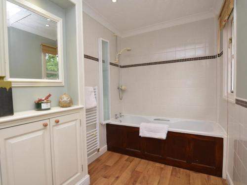 a bathroom with a tub and a sink and a mirror at 2 Bed in Sherborne oc-53673 in Chetnole