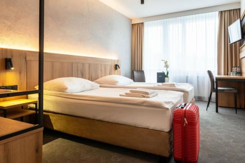 a hotel room with two beds and a red suitcase at Hotel Zawisza in Bydgoszcz
