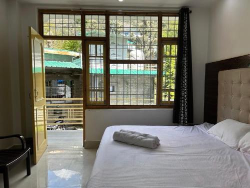 a bed in a bedroom with a large window at OmiHomeStay Dharamkot McLeodganj in Dharamshala
