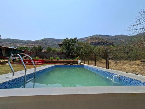 a swimming pool in a yard with a mountain in the background at Girijalsrushti Pool Villa in Kolvan