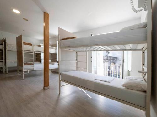 a bedroom with two bunk beds and a large window at mundoalbergue in Santiago de Compostela
