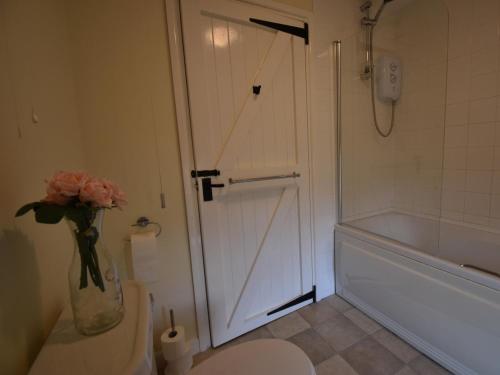 a bathroom with a toilet and a vase of pink roses at 1 Bed in Wareham oc-dc153 in Wool
