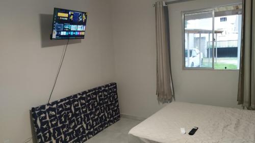 a room with a bed and a television on the wall at Maré Viva Hostel in Aracruz