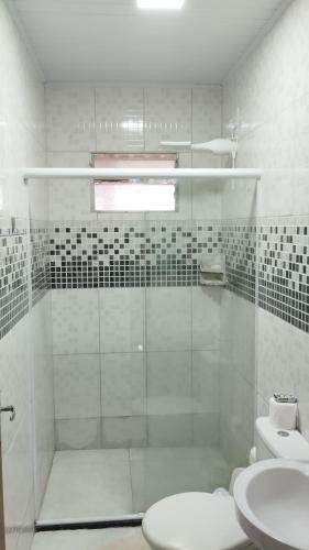 a white bathroom with a shower and a toilet at Maré Viva Hostel in Aracruz