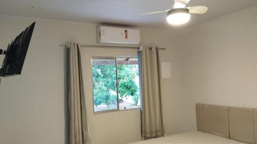 a bedroom with a window and a ceiling fan at Maré Viva Hostel in Aracruz